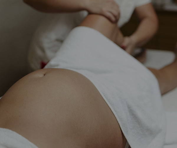 Physical therapist doing lymphatic drainage for the legs of pregnantwoman.
